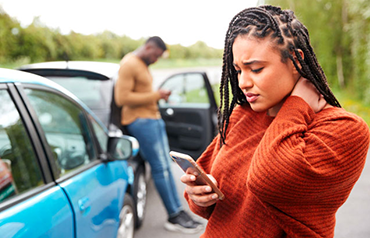 Woman holding neck in pain after car accident, standing next to vehicles symbolizing personal injury