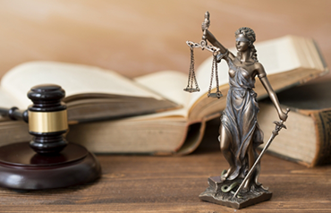 Lady Justice statue with gavel and law books on desk symbolizing Criminal Defense