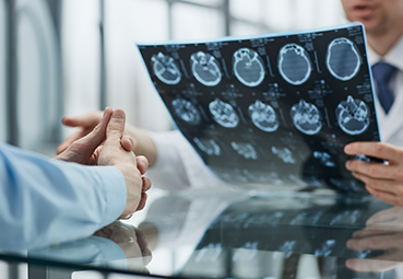 Doctor discussing brain scans with patient in a medical office  symbolizing Traumatic Brain Injuries