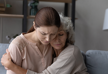 Young woman and elderly woman embracing, both looking sad and emotional symbolizing wrongful Death